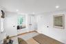 Window seat with integrated storage, wood-finish flooring, recessed lighting, white interior doors with dark hardware, and a window with natural light