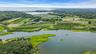 Coastal landscape featuring a large body of water, extensive green areas, and cultivated fields