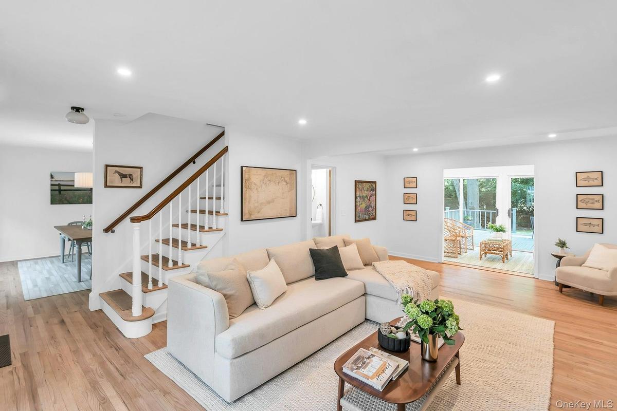 Hardwood flooring throughout, recessed lighting, and a white staircase with wood handrail