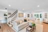 Hardwood flooring throughout, recessed lighting, and a white staircase with wood handrail