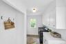 Laundry area featuring wood-finish flooring, white cabinetry, a built-in countertop, and a window