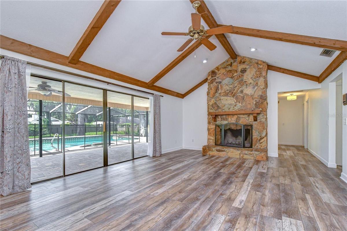 Open gathering space featuring beamed vaulted ceilings and a cozy wood-burning fireplace