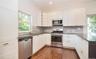 Kitchen featuring stainless steel appliances, open shelves, white cabinetry, dark wood-style flooring, and dark stone counters