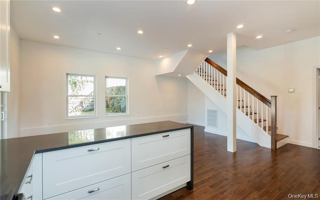 Kitchen with recessed lighting, white cabinets, dark wood finished floors, open floor plan, and dark stone countertops