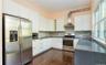 Kitchen featuring stainless steel appliances, open shelves, white cabinetry, wall chimney range hood, and backsplash