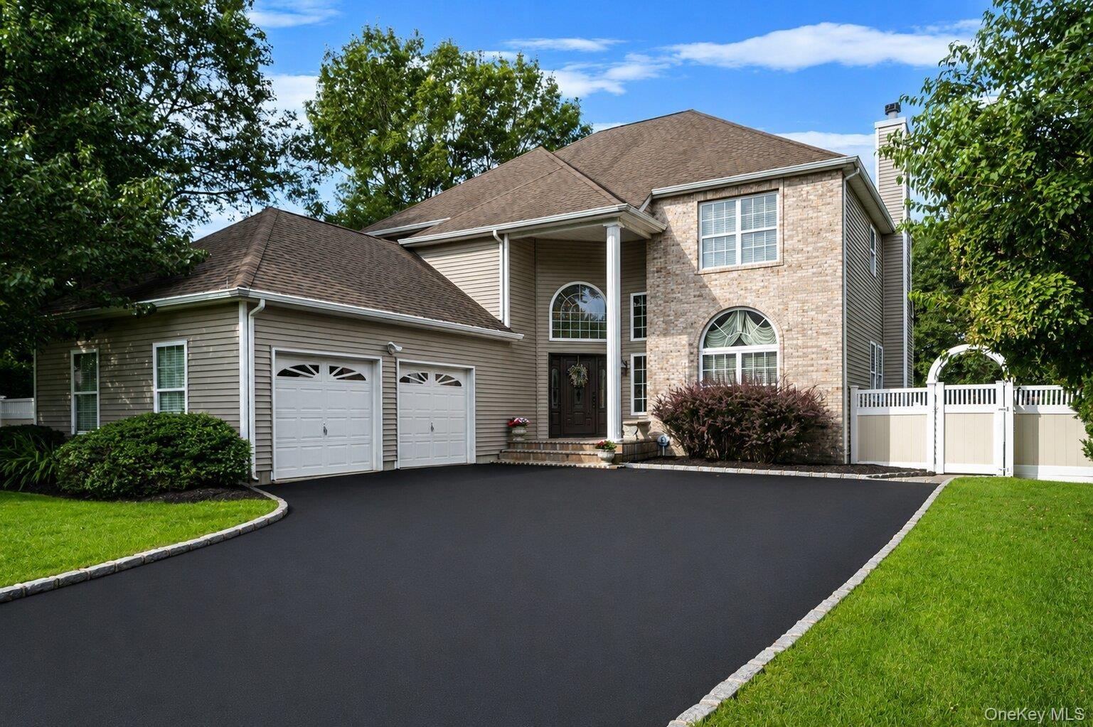 Exterior with brick facade, 2-car garage and wide driveway.