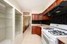 Kitchen featuring wood cabinetry, a black tile backsplash, light-colored countertops, and a white gas range