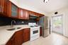 Kitchen featuring wood-finish cabinetry, light-toned countertops, a stainless steel sink with a gooseneck faucet, a tile backsplash, and a stainless s