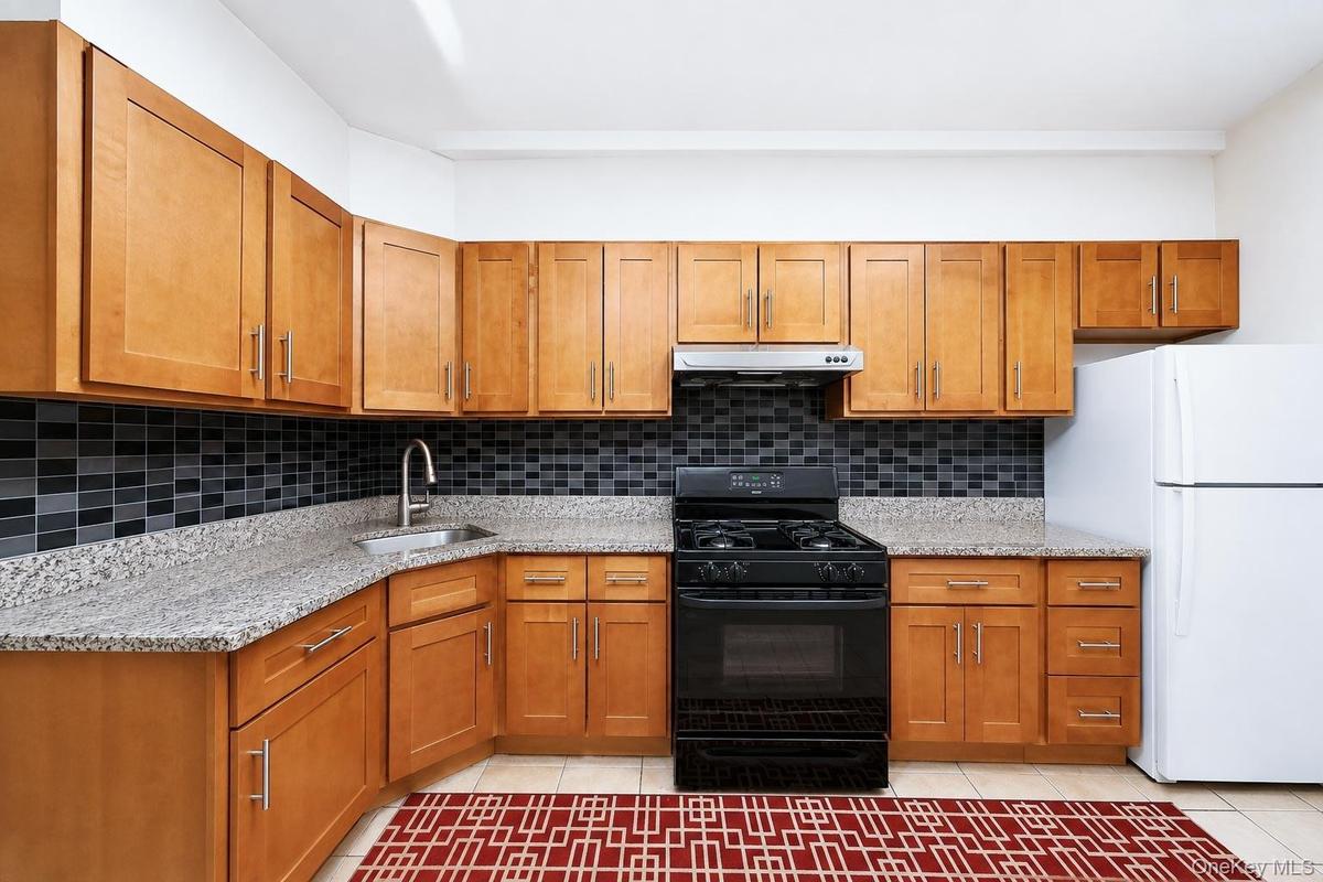 U-shaped kitchen featuring wood-finish cabinetry, light-toned countertops, and a full tile backsplash