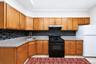 U-shaped kitchen featuring wood-finish cabinetry, light-toned countertops, and a full tile backsplash