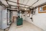Utility space featuring two water heaters, a furnace, and two windows with wood trim