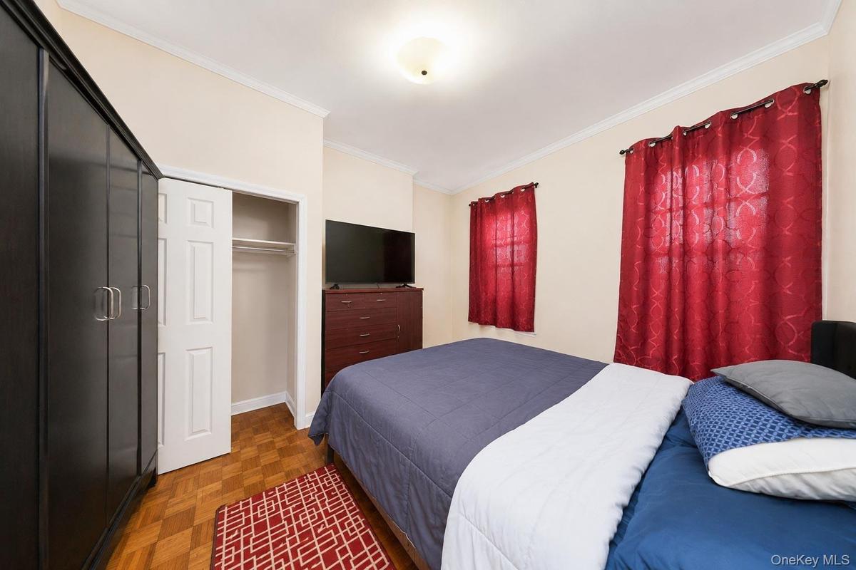 Warm tone walls with crown molding, wood-finish flooring, and a flush-mount ceiling light