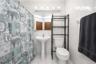 White tiled walls, pedestal sink, toilet, and overhead vanity lighting