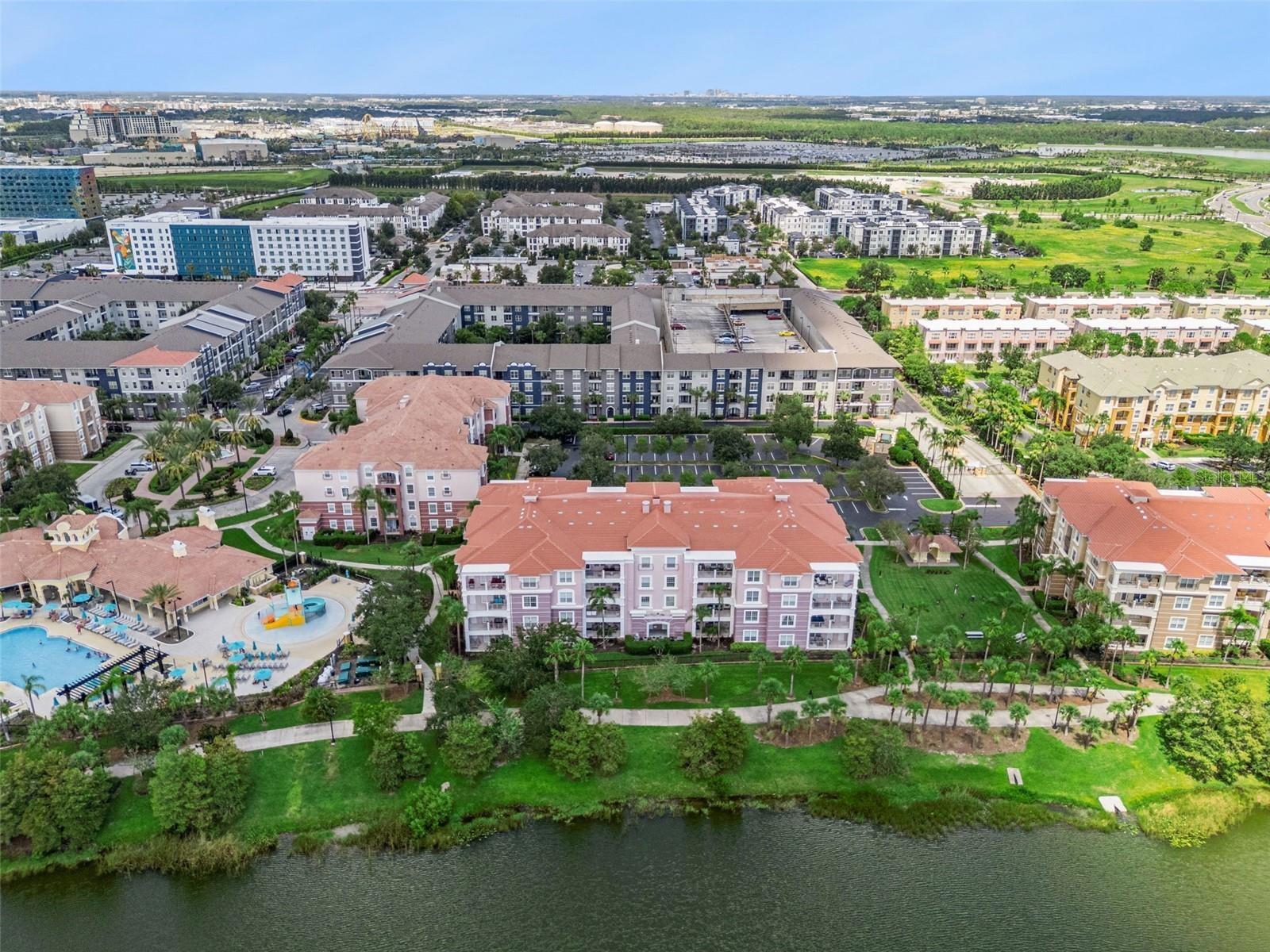 Building & Lakefront Aerial:Direct aerial overview of the building's lakefront position, adjacent pool complex, manicured lawn, and surrounding Orland