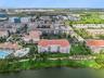 Building & Lakefront Aerial:Direct aerial overview of the building's lakefront position, adjacent pool complex, manicured lawn, and surrounding Orland