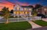 Two-story exterior with siding, a covered front porch, a white picket fence, and a manicured lawn
