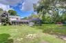 Expansive lawn extends beyond the screened enclosure with abundant room for recreation