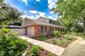 Side view showcasing the classic brick exterior, fresh front landscaping, and wide paved driveway.