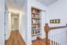 Upper hallway featuring custom built-in shelving and warm flooring.