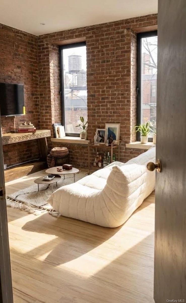 3 large windows, lots of light, staged for hanging out and watching tv.
