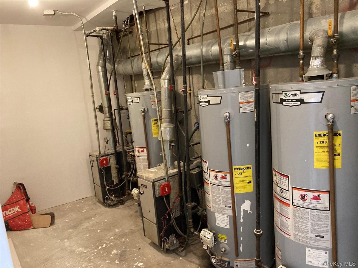 Mechanical area featuring dual commercial-grade water heaters and dual boilers with overhead metallic ductwork