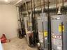 Mechanical area featuring dual commercial-grade water heaters and dual boilers with overhead metallic ductwork