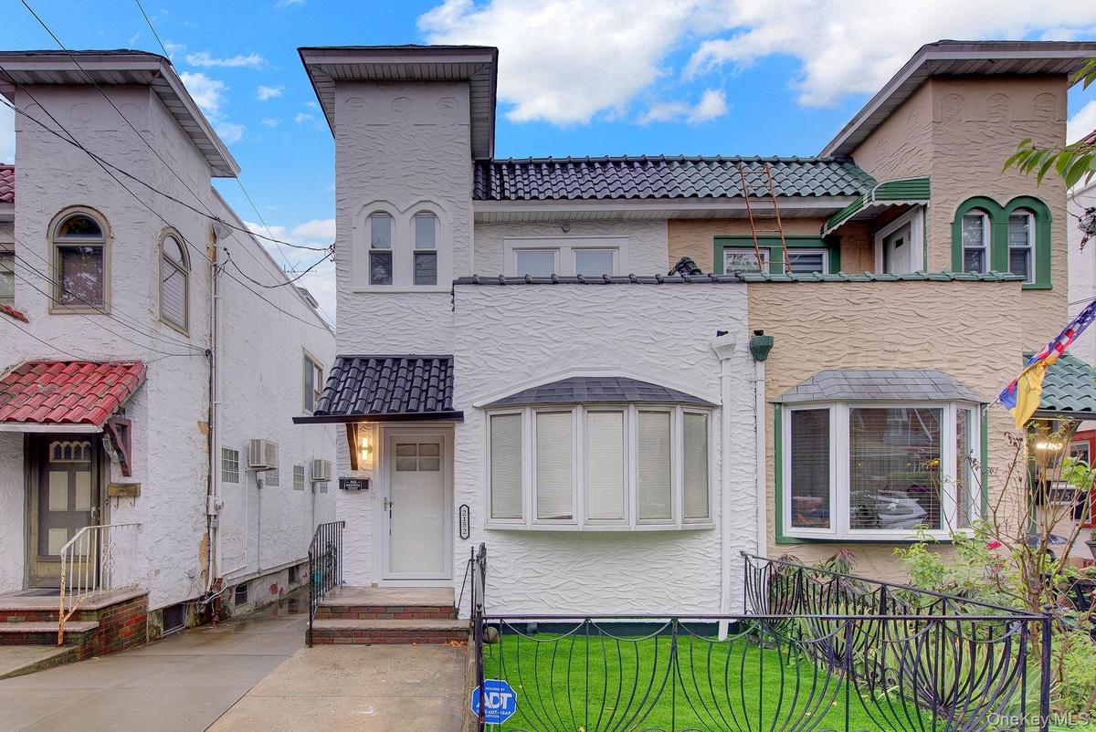 White stucco exterior with a tiled entry awning and bay window