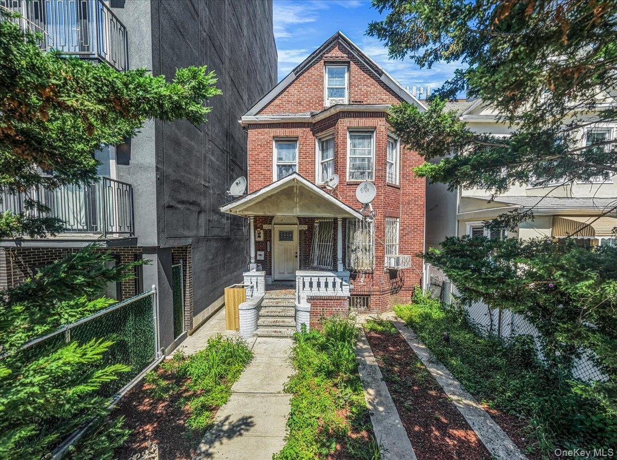 Brick facade with bay window, covered porch, and concrete walkway