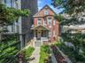 Brick facade with bay window, covered porch, and concrete walkway