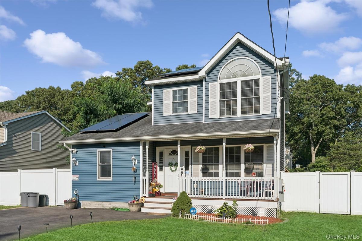 Two-story exterior with blue siding, a covered front porch, an arched window, and solar panels