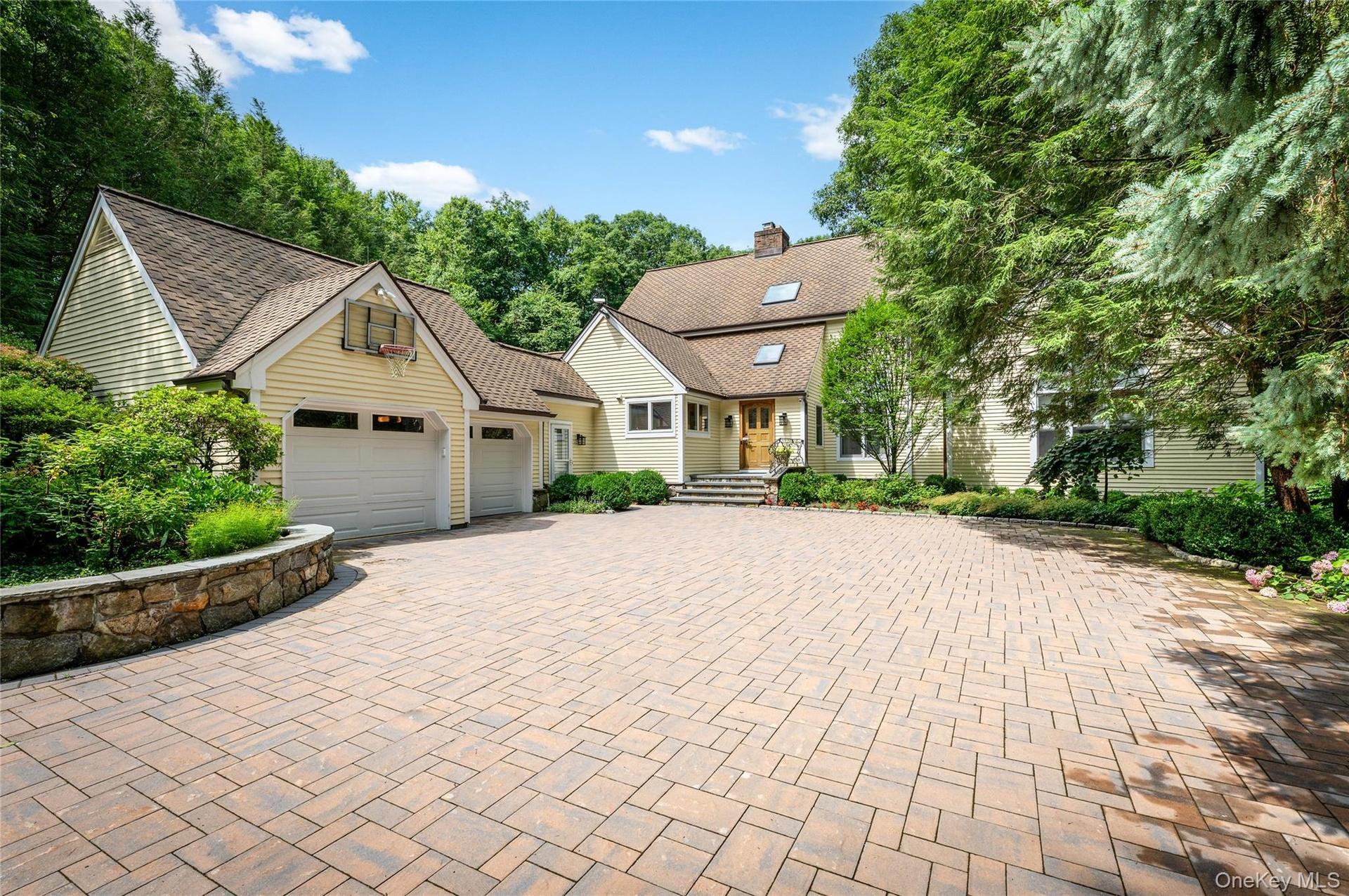 Large driveway, designed with pavers, Belgium block edging and stone wall.