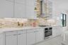 Contemporary kitchen with white high-gloss cabinetry, stainless steel range hood, built-in oven, and a gas cooktop