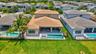 Rear exterior with a spacious green lawn, a rectangular pool with an integrated spa, and an expansive covered patio