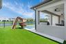 Resort-style backyard featuring a pool with a slide, artificial turf, and a lake