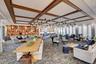 Spacious common area featuring a coffered ceiling with dark wood-finish beams, a large decorative chandelier, a built-in display wall with multiple cu