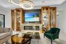Living area featuring a contemporary linear fireplace with a gold-toned surround, a media wall with a mounted television, and a coffered ceiling with 