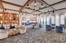 Spacious common area featuring a coffered ceiling with multiple pendant lights, an integrated bar area, large windows with vertical blinds, a built-in