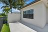Exterior patio featuring large format tile flooring, a privacy wall, and three dark-framed windows
