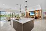 Spacious open-concept interior featuring a large kitchen island with a white countertop and integrated sink, glossy cabinetry, built-in shelving, a wa