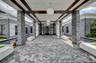 Covered entryway featuring stacked stone columns and wood beam ceiling accents