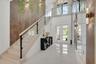 Grand foyer featuring a two-story ceiling, polished floor tiles, and a staircase with a light wood-finish handrail and glass panels