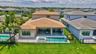 Rear exterior showcasing a private pool with an integrated spa, an expansive paver patio, a covered lanai, and a substantial fenced lawn area