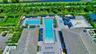 Expansive outdoor amenity area featuring multiple swimming pools, extensive lounge seating, shaded cabanas, a designated splash pad, and a children's 