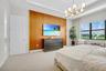 Spacious room featuring a prominent wood panel accent wall, large window with outdoor landscaping, tray ceiling, and a contemporary chandelier