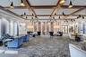 Spacious room featuring a coffered ceiling with wood-finish beams, multiple contemporary light fixtures, patterned accent wall panels, and large windo