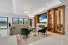 Spacious living area featuring high ceilings with recessed lighting and decorative chandeliers, large format tile flooring, and sliding glass doors op