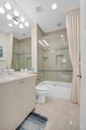 Contemporary bathroom featuring a light-toned vanity with an integrated sink, a full-width mirror, and a tub with a glass shower enclosure