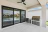 Covered patio featuring an outdoor kitchen with built-in stainless steel grill and cabinetry, refrigerator, ceiling fan, and large format tile floorin