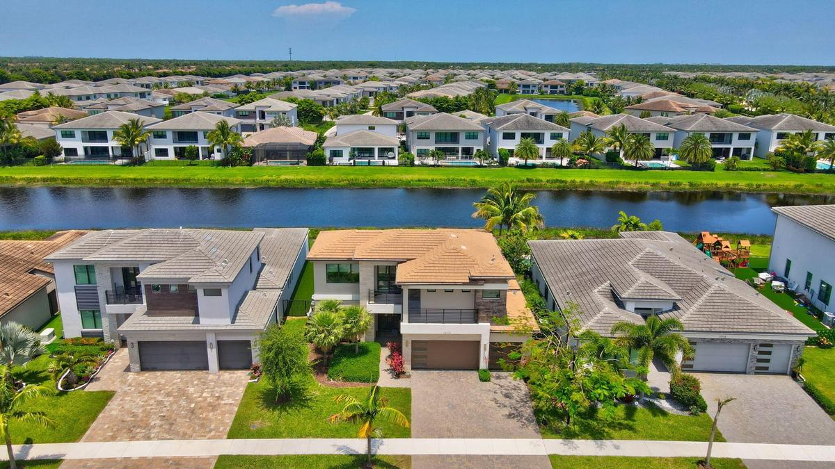 Contemporary two-story residence featuring a tile roof, a two-car garage, and a paver driveway