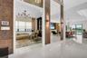 Expansive main living area featuring glossy white tile flooring, a large mirrored wall with integrated sconce lighting, and a view into an adjacent ro